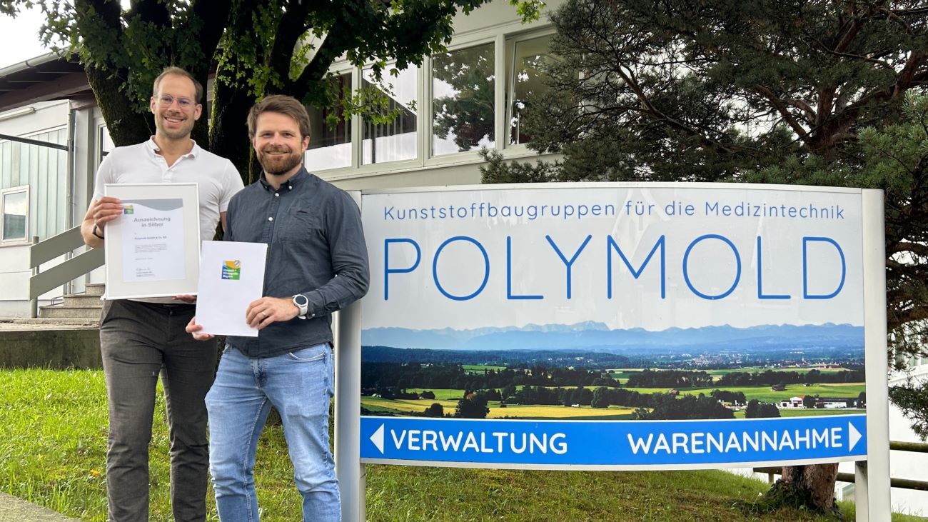 POLYMOLD wird für langjähriges Engagement im Umwelt- und Klimaschutz geehrt. Geschäftsführer Jonathan Welz (li.) und Entwicklungsingenieur Gereon Starke (re.) mit der Silber-Urkunde vom Umweltpakt Bayern.